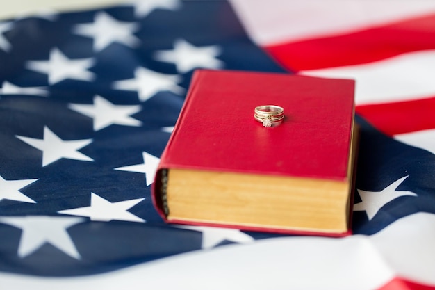 diritti civili, valori familiari e concetto di matrimonio - primo piano della bandiera americana e fedi nuziali su libro o bibbia