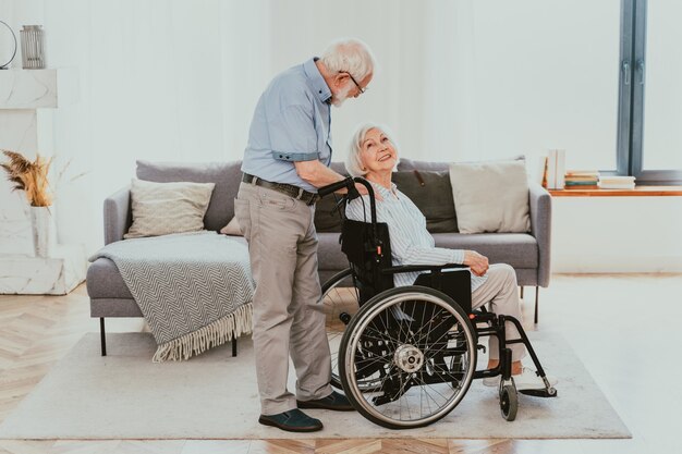 Disabile vecchio su sedia a rotelle coppia senior a casa partner di ritorno dall'ospedale