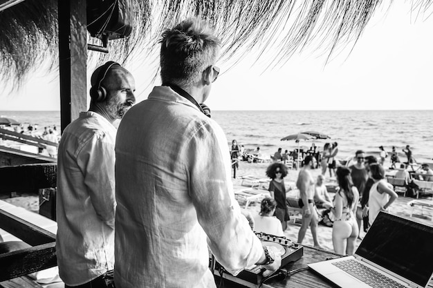 Disc jockey che suonano musica per turisti al club party all'aperto sulla spiaggia Dj che indossano le cuffie all'evento musicale dal vivo Concetto di musica e divertimento Concetto di intrattenimento e festa