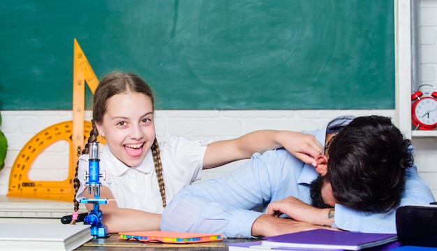 Discipline scolastiche STEM. conoscenza educativa. insegnante uomo barbuto con piccola ragazza in classe. lezione di chimica biologia. di nuovo a scuola. geometria matematica. padre dorme e figlia studiano in classe.