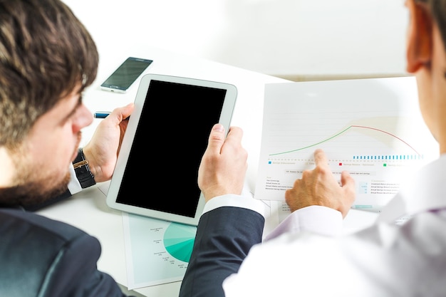 Discussione sull'analisi dei dati utilizzando un tablet e materiali di presentazione in un ambiente di ufficio moderno