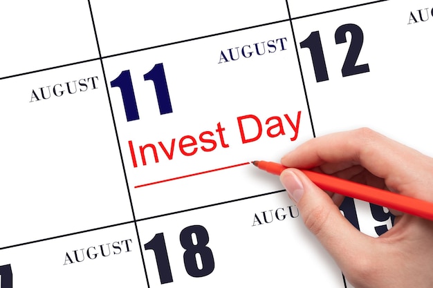 Disegnare a mano la linea rossa e scrivere il testo Invest Day sulla data del calendario 11 agosto Concetto di business e finanziario