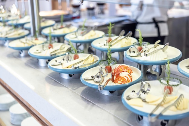 Disegnare in modo creativo il tavolo del buffet nel ristorante dell'hotel Pomodori con mozzarella e olive su un piatto ha portato altri piatti di formaggio ed erbe aromatiche