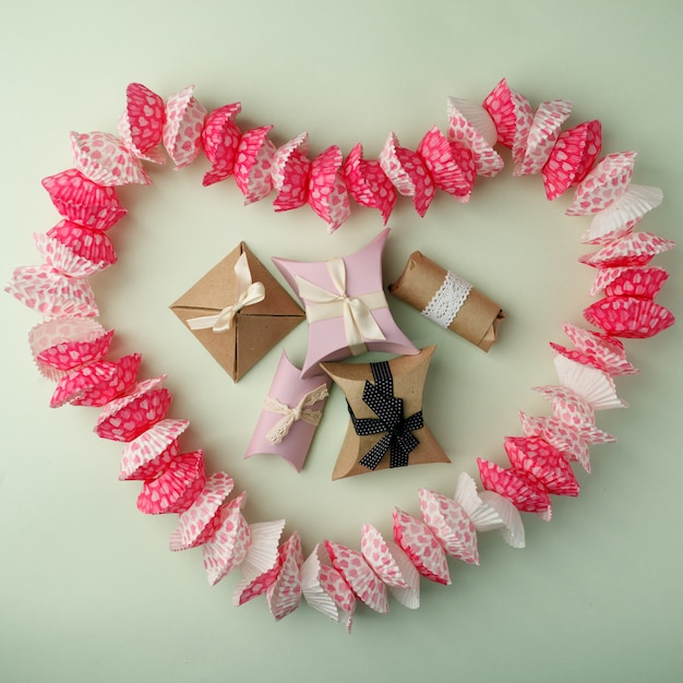 Disegnato a forma di cupcake a forma di cuore e scatole regalo su uno sfondo verde pastello, copia spazio, alto, vista