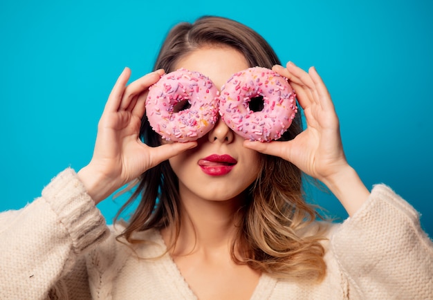 Disegni la donna in maglione con la ciambella sulla parete blu