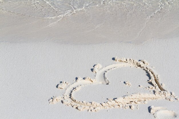 Disegno del cuore sulla spiaggia con l'onda.