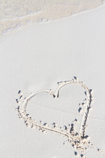 Disegno del cuore sulla spiaggia con l'onda.