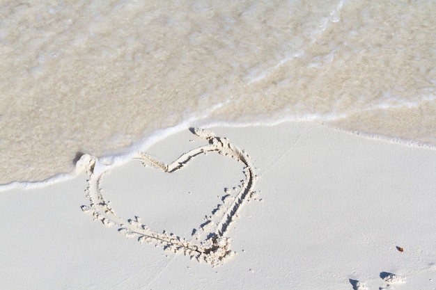 Disegno del cuore sulla spiaggia con l'onda.