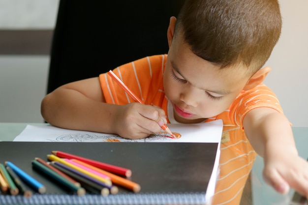 Disegno del ragazzo carino con le matite di colore, concetto di apprendimento del capretto