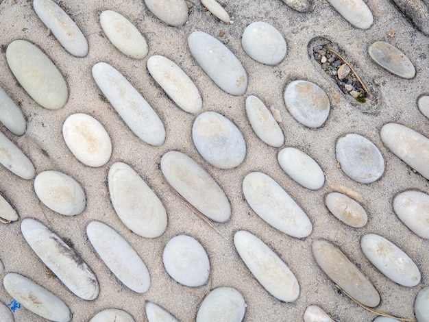 Disegno di pietre marine in cemento Copertura del suolo nel parco Sfondio con urti Sfondio di ciottoli di spiaggia e cemento Disegno insolito