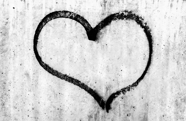 Disegno di un cuore nero su un muro di cemento