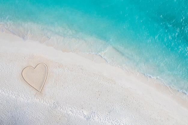 Disegno perfetto di forma di cuore in sabbia soffice bellissimo sfondo marino. San Valentino romantico