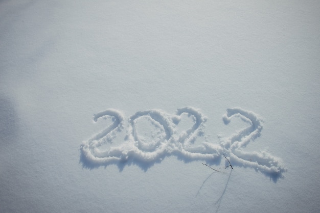 Disegno sulla neve bianca. Data di Capodanno, cifre 2022, primo piano.