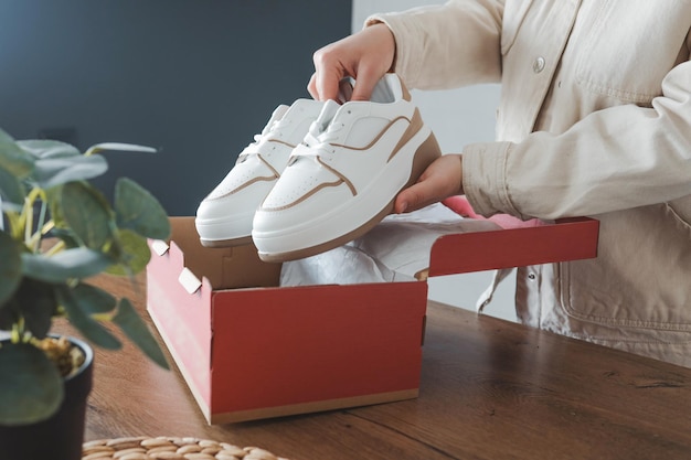 Disimballaggio delle scarpe da donna eleganti sneakers bianche nelle mani