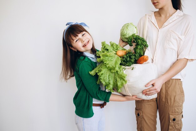 Disimballaggio di un sacchetto ecologico di verdure fresche e verdure dopo la spesa di due ragazze. Mangiare sano concetto.