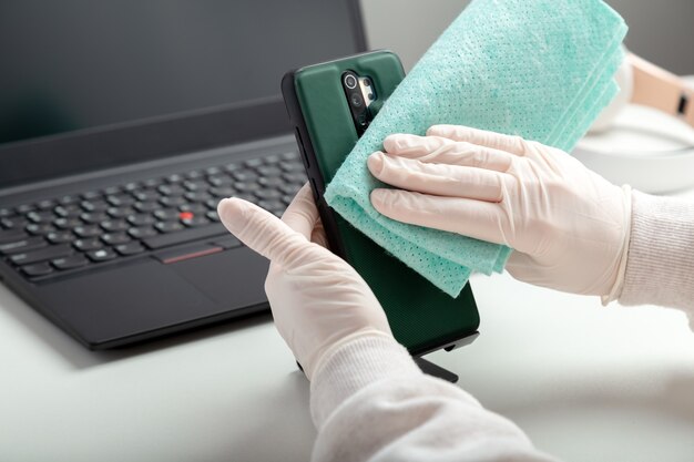 Disinfettare la casa con disinfettante alcolico. La donna in guanti medici pulisce la casa con tessuto e disinfettante durante il covid 19. Protezione prevenzione igienica da infezione da coronavirus, germi, batteri.