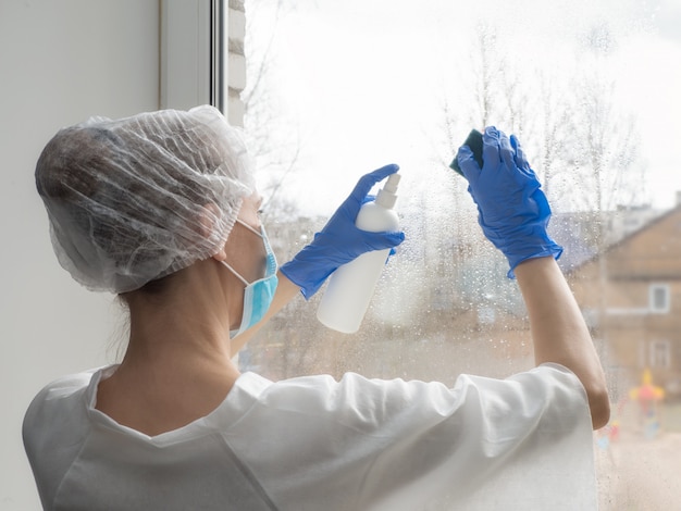 Disinfezione da coronavirus. Le persone a fare disinfezione su Windows. Il medico in guanti di gomma disinfetta le finestre con disinfettante e spugne