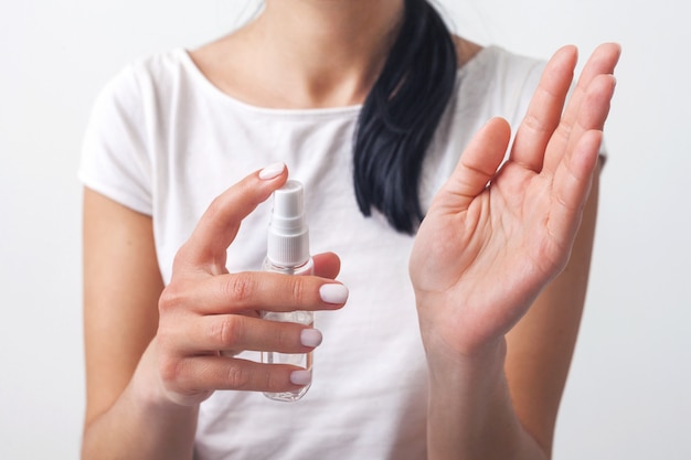 Disinfezione delle mani. La mano di Lady prende sulle sue mani spray disinfettante con alcool. Isolato su un bianco