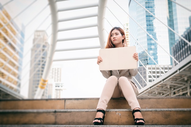 Disoccupazione. Giovane donna di affari con il segno che cerca un lavoro.