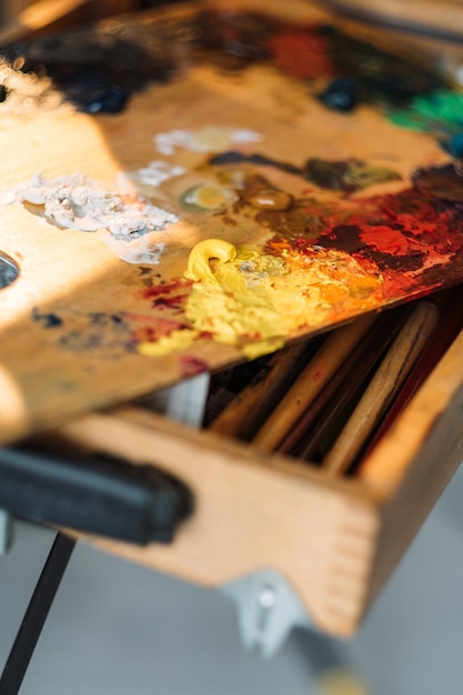 Disordine dell'artista Strumenti di pittura Arte professionale Hobby creativo Striature di colore della pittura a olio rosso giallo sulla vecchia tavolozza di legno vintage sporca sul supporto del pennello