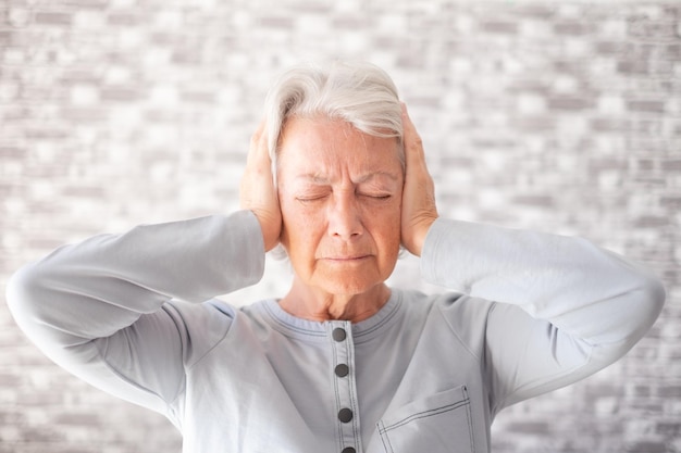 Disperata donna anziana frustrata nel dolore con le mani sulle orecchie donna anziana da sola a casa che soffre