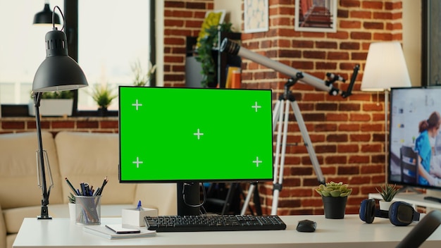Display a schermo verde su computer con scrivania vuota in soggiorno, area di lavoro con sfondo bianco chroma key. Mostra copyspace isolato con modello mokcup sul monitor desktop a casa.