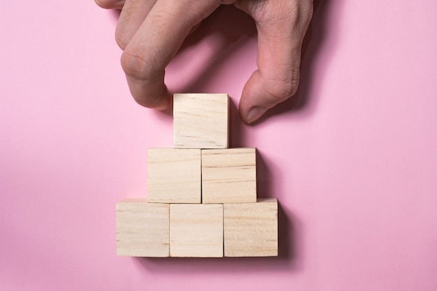 disposizione a mano cubo di legno accatastamento a forma di piramide. crescita aziendale e concetto di gestione