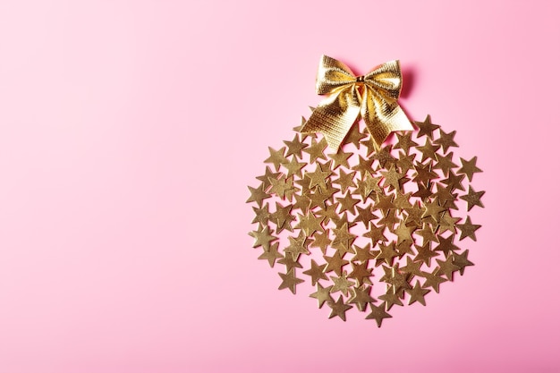 Disposizione creativa di Natale con stelle dorate in cerchio su sfondo rosa, concetto di glamour