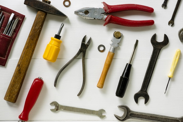 Disposizione degli strumenti di riparazione e costruzione su un fondo di legno bianco