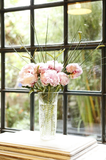 Disposizione dei fiori di peonie in vaso di vetro sul tavolo