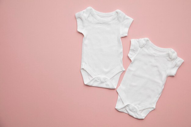 Disposizione del vestito bianco del bambino sveglio su uno sfondo rosa pastello