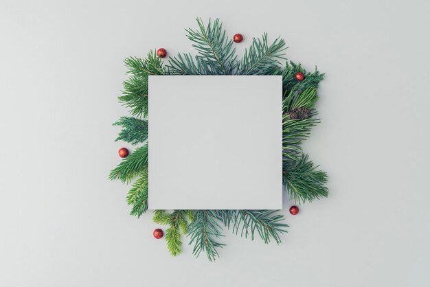 Disposizione di Natale di una nota quadrata e rami di abete su sfondo bianco