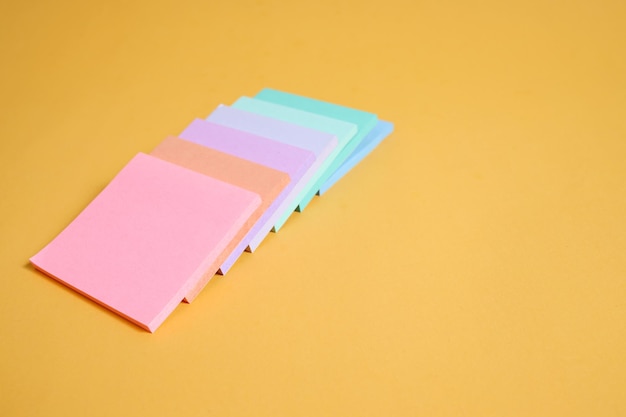 Disposizione di pile di note adesive colorate isolate su sfondo giallo