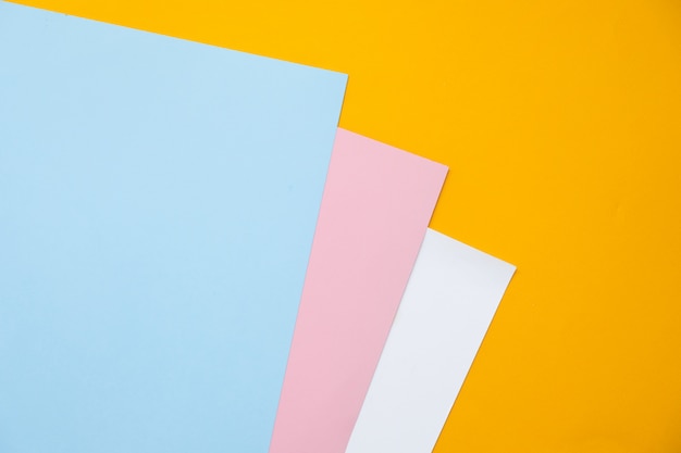 Disposizione geometrica piana di carta di colore pastello blu, giallo e rosa