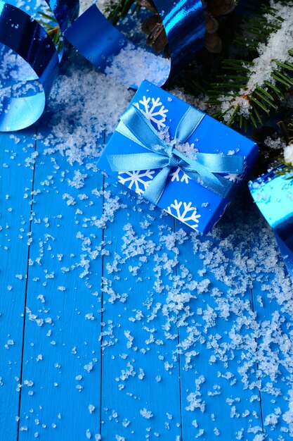 Disposizione magica della confezione regalo blu con nastri e rami di pino nella neve.