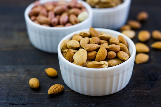 Disposizione matta saporita in una ciotola su una tavola di legno. Cibo sano e snack, cibo vegetariano biologico. Noce, mandorla, arachidi