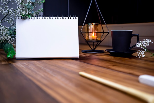 Disposizione piana del taccuino bianco in bianco con il caffè della tazza sulla tavola di legno.