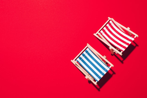 Disposizione piana delle sedie a sdraio della spiaggia su fondo rosso con lo spazio della copia.