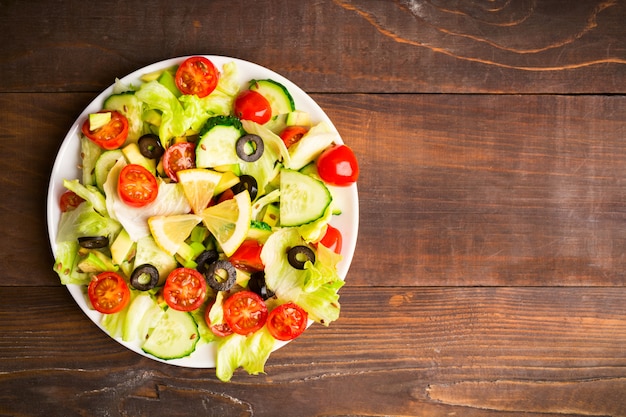 Disposizione piana di insalata verde e rossa con il limone e il seme su fondo di legno