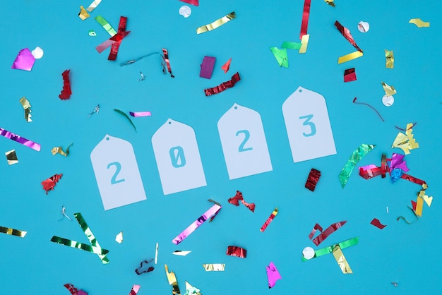 Disposizione piana festiva dell'anno 2023 con coriandoli colorati su sfondo blu