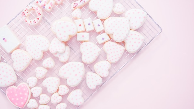 Disposizione piatta. Biscotti di zucchero a forma di cuore decorati con glassa reale su stendino.