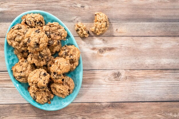 Disposizione piatta. Biscotti gommosi appena sfornati dell'uva passa della farina d'avena su un piatto blu.