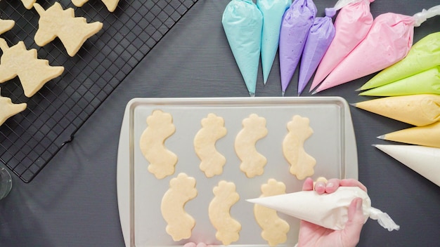 Disposizione piatta. Decorare i biscotti di zucchero unicorno con glassa reale multicolore.