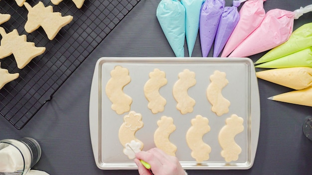 Disposizione piatta. Decorare i biscotti di zucchero unicorno con glassa reale multicolore.