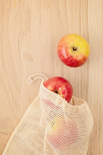 Disposizione piatta del sacchetto di cotone a rete riutilizzabile ecologico con mele. Concetto di stile di vita sostenibile, etico, senza plastica e zero rifiuti. Vista dall'alto