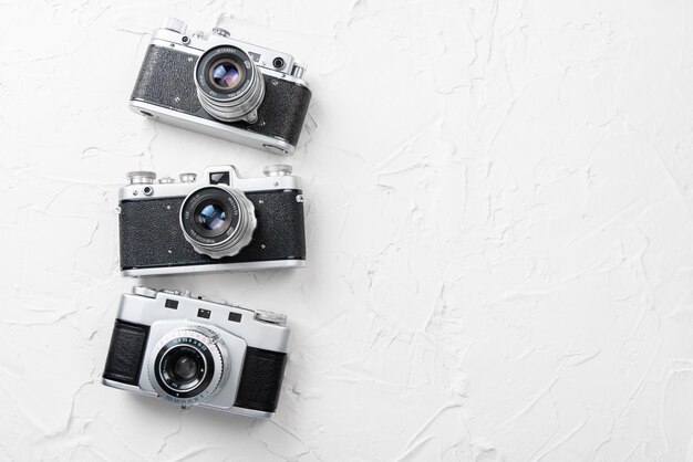 Disposizione piatta di tre vecchie macchine fotografiche vintage su sfondo bianco con spazio libero per il testo mock up