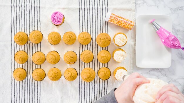 Disposizione piatta. Glassa di crema al burro italiana convogliata sopra il cupcake alle spezie di zucca.