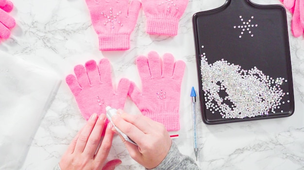 Disposizione piatta. Guanti rosa per bambini con strass a forma di fiocco di neve.