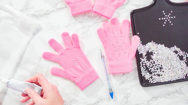 Disposizione piatta. Guanti rosa per bambini con strass a forma di fiocco di neve.