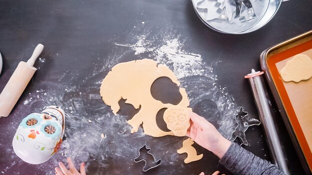 Disposizione piatta. Madre e figlia che cuociono biscotti con teschio di zucchero per la festa di Dia de los Muertos.